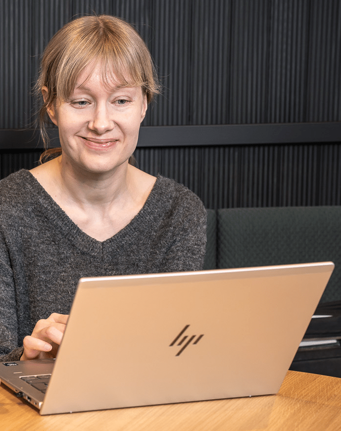 HJP-Kehitys-Oy-Iisalmi-Savo-palvelua-teamsin-valityksella-koko-Suomeen Nuori nainen kannettavan tietokoneen aarella.